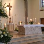 Altar sereno de igreja decorado com velas e flores para o dia do santo, 14 de março de 2025.
