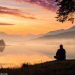 Paisagem tranquila ao amanhecer com um lago calmo, simbolizando a reflexão espiritual.