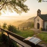 Nascer do sol tranquilo sobre uma capela no campo, com luz dourada suave entre as árvores e uma Bíblia aberta em um banco de madeira