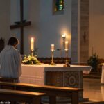 Interior sereno de uma igreja durante a Missa de Domingo, com iluminação suave e um ambiente calmo, destacando um altar iluminado por velas.