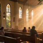 Imagem de uma igreja no campo com luz do sol entrando pelos vitrais enquanto pessoas oram em silêncio