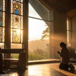 Pessoa ajoelhada em oração dentro de uma igreja iluminada pelo sol da manhã