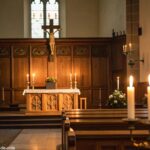 Ambiente tranquilo de igreja com altar de madeira e luz suave de velas, simbolizando reflexão e oração.