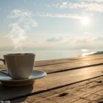 Cena tranquila de manhã com luz suave, uma xícara de café sobre uma mesa de madeira e um céu calmo ao fundo, simbolizando uma manhã abençoada na sexta-feira.