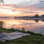 Amanhecer sereno sobre um lago calmo com cores suaves no céu