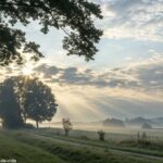 Paisagem ao amanhecer com luz suave e uma cruz ao fundo representando fé para quarta-feira