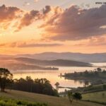 Nascer do sol sereno sobre uma paisagem tranquila com luz dourada suave filtrando através de nuvens gentis