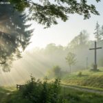 Cenário de manhã serena com luz suave e cruz de madeira ao fundo