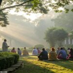 Cena tranquila de manhã com luz suave do sol filtrando através das árvores em um jardim sereno. Um grupo de pessoas de idades e origens diversas reunidas em oração, simbolizando a unidade na fé.