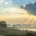 Cena tranquila de manhã com raios de sol passando pelas nuvens sobre uma paisagem calma