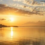 Nascer do sol sereno sobre águas calmas com reflexos dourados, simbolizando reflexão e inspiração