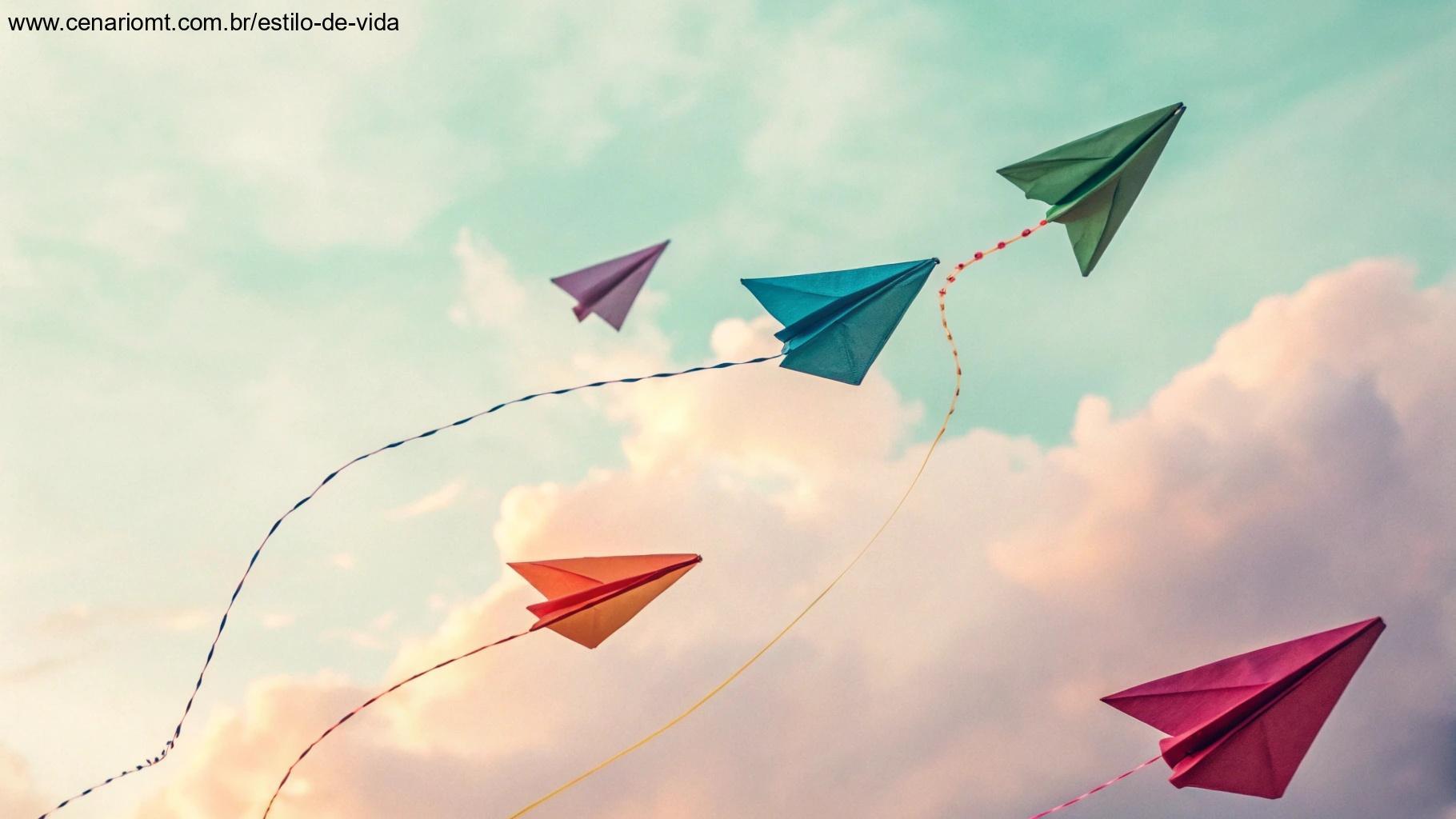 Aviões de papel coloridos voando contra um fundo pastel