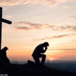 Cruz silhouetada ao amanhecer, simbolizando oração e reflexão.