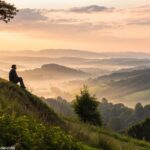 Pessoa orando ao amanhecer em um vale tranquilo, inspirando reflexão sobre o Salmo do Dia