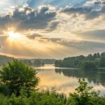 Paisagem serena ao amanhecer, com luz suave do sol rompendo as nuvens sobre um lago tranquilo rodeado por árvores verdes, simbolizando esperança e refúgio