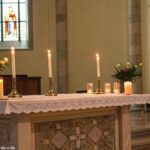 Cena serena de um altar de igreja com velas acesas, representando reflexão e fé para o Santo do Dia: Quinta-feira, 24 de Abril de 2025.