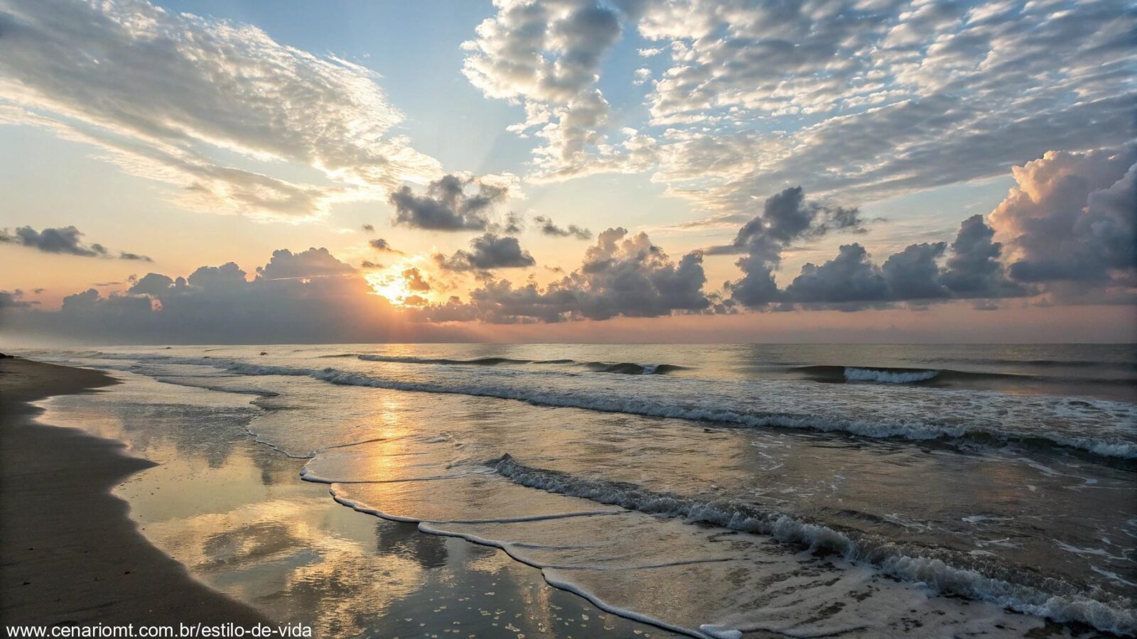 Imagem de um amanhecer tranquilo sobre um cenário sereno, com nuvens suaves no céu e ondas suaves batendo na praia, evocando uma sensação de calma e espiritualidade.