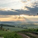 Paisagem ao amanhecer com cruz ao fundo representando fé e esperança