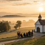 Imagem de um nascer do sol sereno sobre o campo, iluminando uma capela com pessoas em oração, simbolizando fé e esperança para a manhã de quarta-feira