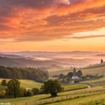Imagem de um nascer do sol vibrante sobre uma paisagem tranquila, simbolizando um novo começo e energia positiva para o dia.