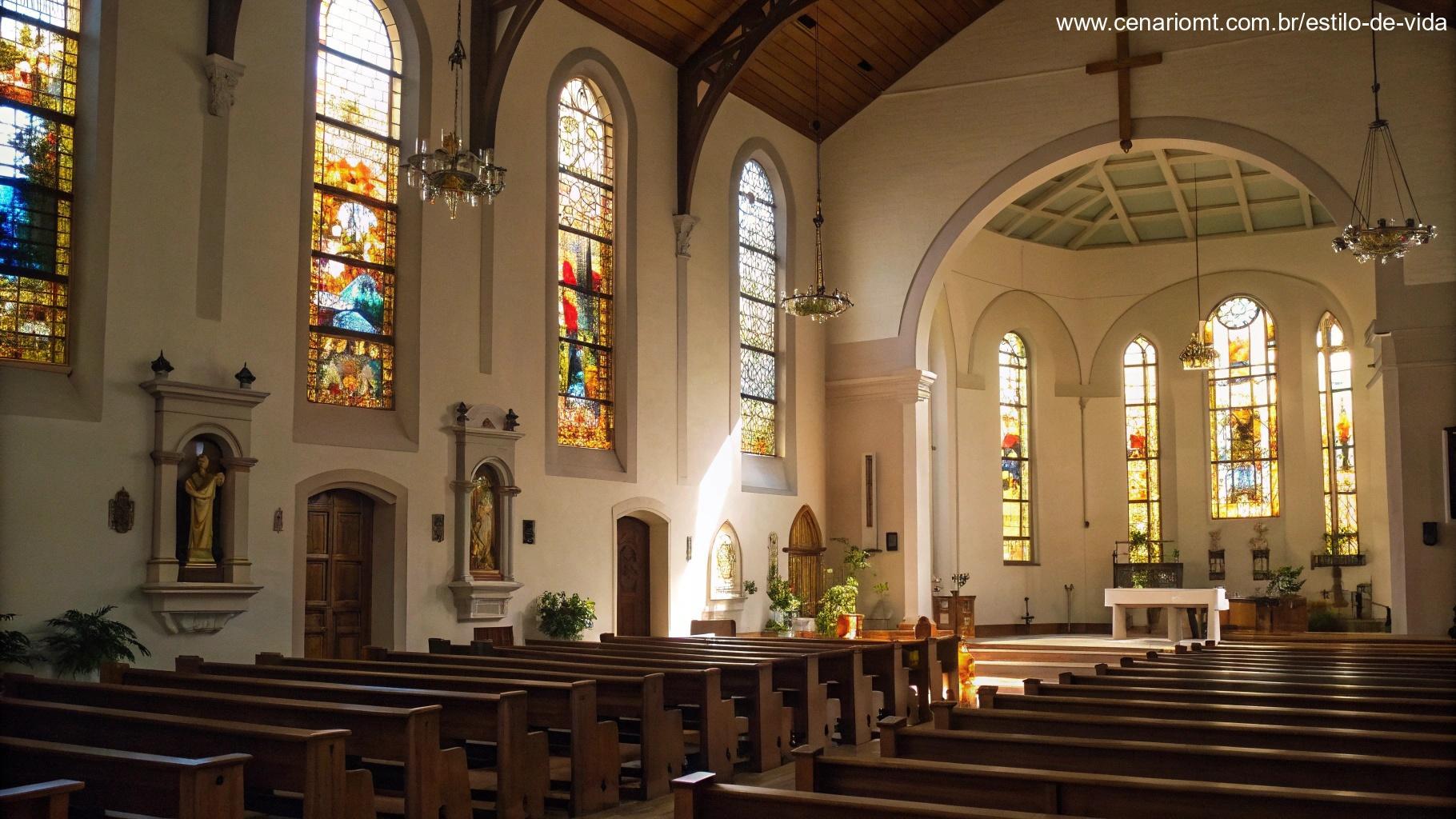 Imagem do interior tranquilo de uma igreja, com luz filtrando pelas janelas de vitrais, criando uma atmosfera sagrada.