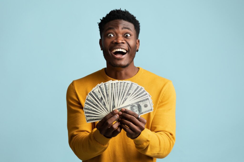 Afortunado cara afro-americano segurando um monte de dinheiro - Fotos do Canva