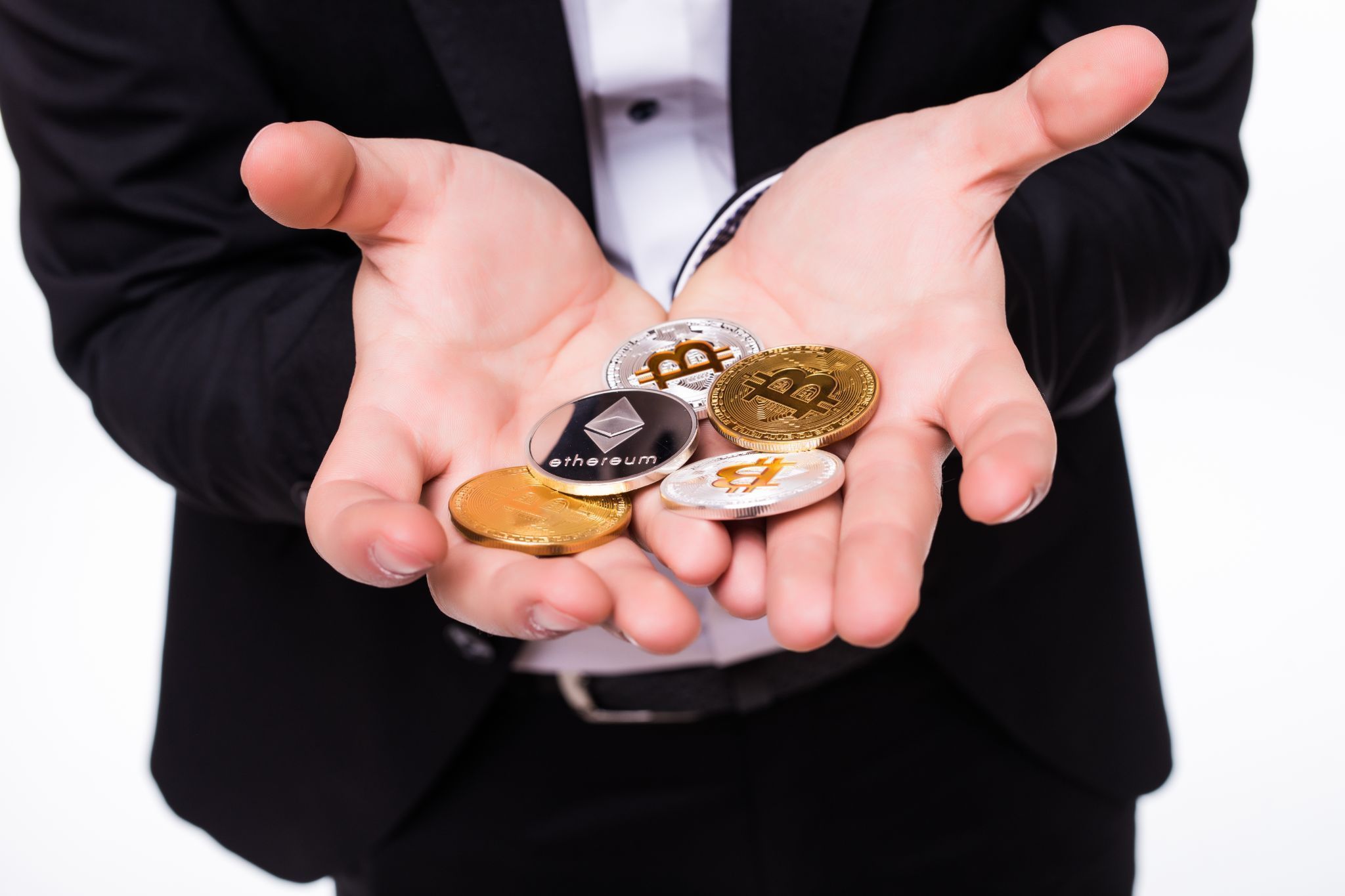 man holds different crypto coins in his hands on white