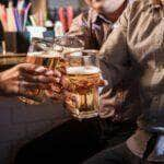 happy friends drinking beer at counter in pub