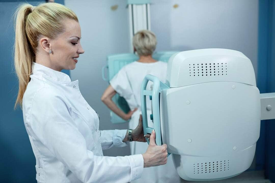 enfermeira sorridente adulta media tomando raio x de um paciente na clinica