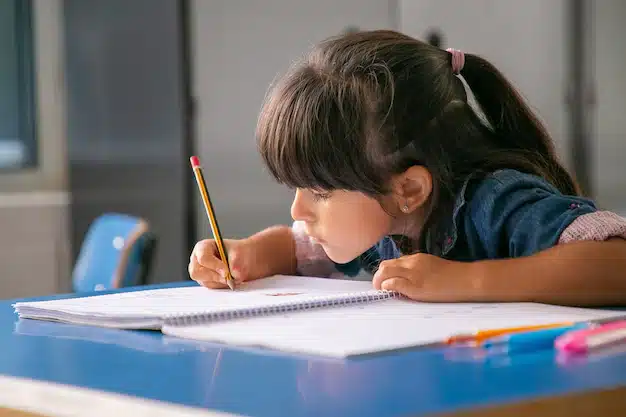 garota latina de cabelo concentrado sentada na mesa da escola e desenhando em seu caderno 74855 16368