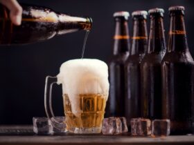 garrafas de vidro de cerveja com vidro e gelo no fundo escuro