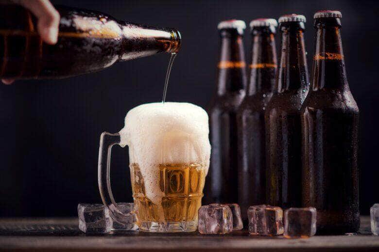 garrafas de vidro de cerveja com vidro e gelo no fundo escuro