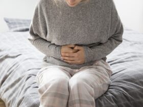 mulher doente com as maos no estomago sofrendo de dor intensa