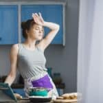 mulher limpando testa em cozinha