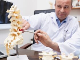 osteopata apontando para o modelo de inflamacao da coluna no consultorio medico