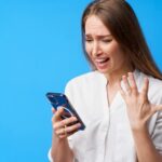 retrato de uma jovem mulher com raiva usando o telefone irritada enviando mensagens de texto com alguem com fundo azul 93675 114208