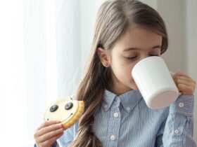 uma menina da escola primaria esta tomando cafe da manha com leite e biscoitos engracados na forma de um smiley
