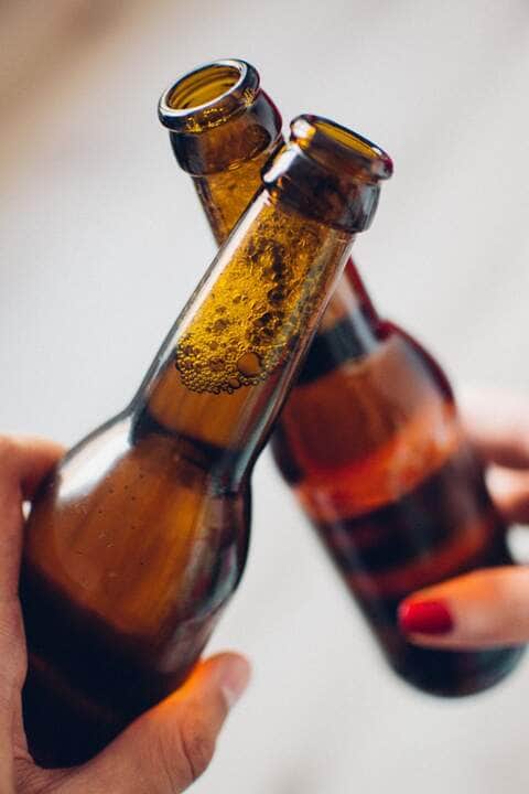 Homem com barriga grande segurando garrafa de cerveja em casa - Fotos do Canva