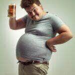 Pessoa com barriga grande segurando copo de cerveja - Fotos do Canva