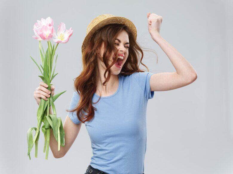 Mulher jovem feliz segurando flores - Fotos do Canva