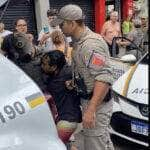 Brasília (DF) 17/02/2024 - vítima negra que sofreu a tentativa de homicídio sendo presa enquanto o agressor branco ri tranquilamente falando com a policial. . Foto: nietzsche4speed/X