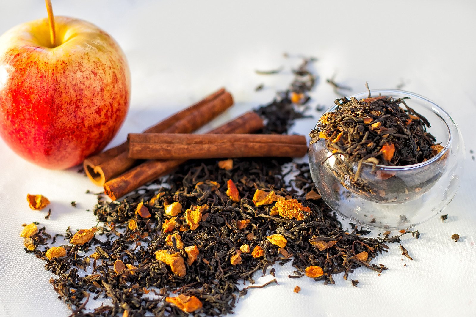 Chá de ervas com frutas secas, canela em pau, copo de maçã em fundo branco - Fotos do Canva