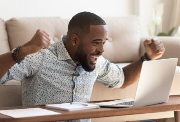 Homem Africano animado ler mensagem no computador comemorando a oportunidade recebida - Fotos do Canva