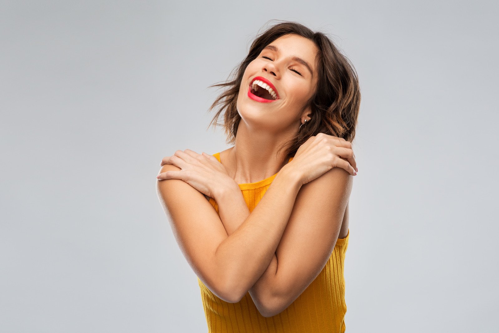 Mulher jovem e feliz e agradecida em um top amarelo mostarda - Fotos do Canva