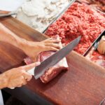 Açougueiro sorridente cortando carne no balcão - Fotos do Canva