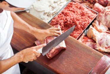 Açougueiro sorridente cortando carne no balcão - Fotos do Canva