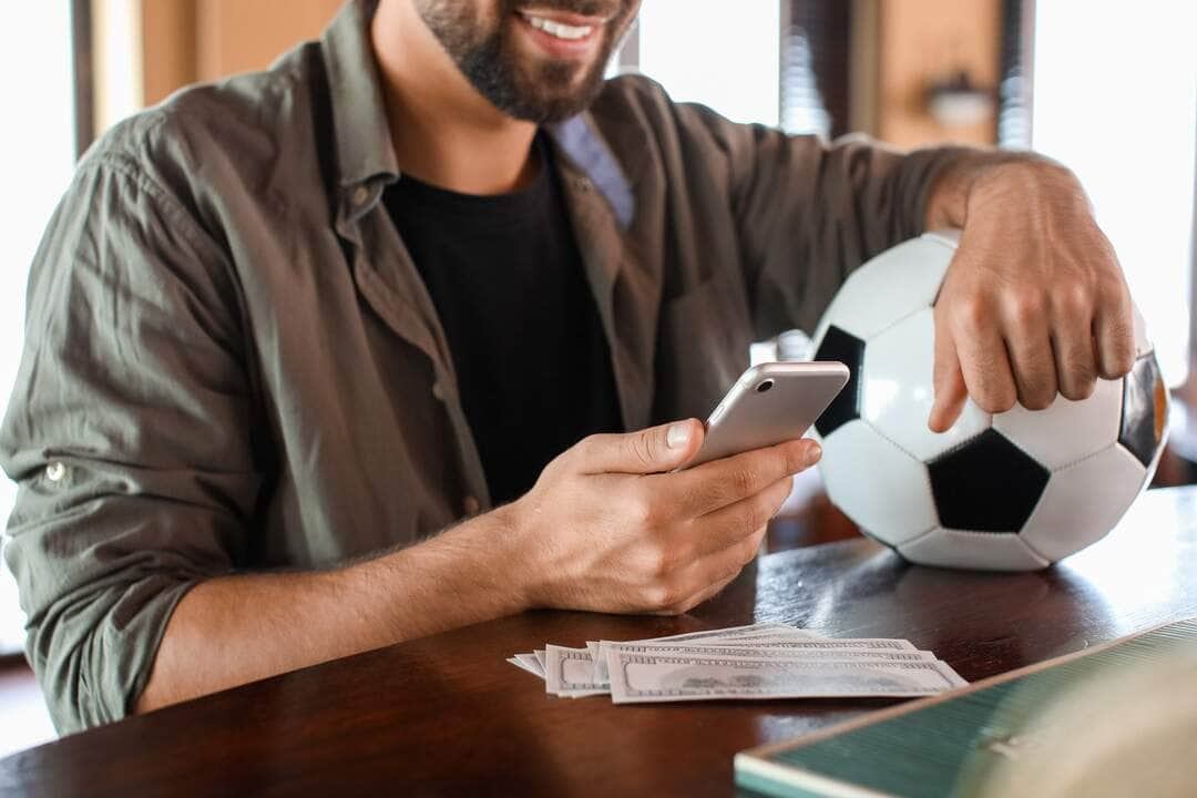 Jovem fazendo apostas esportivas em um pub - Fotos do Canva