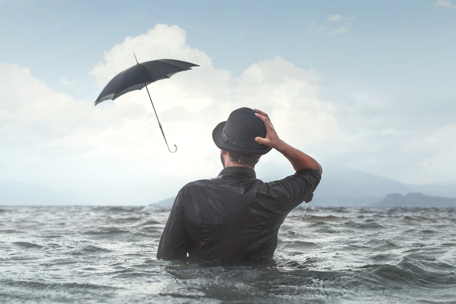 Maré de azar, homem no meio do oceano com guarda chuva- Fotos do Canva