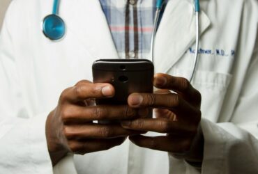 Médico com estetoscópio fala no celular. Foto: National Cancer Institute/Unsplash