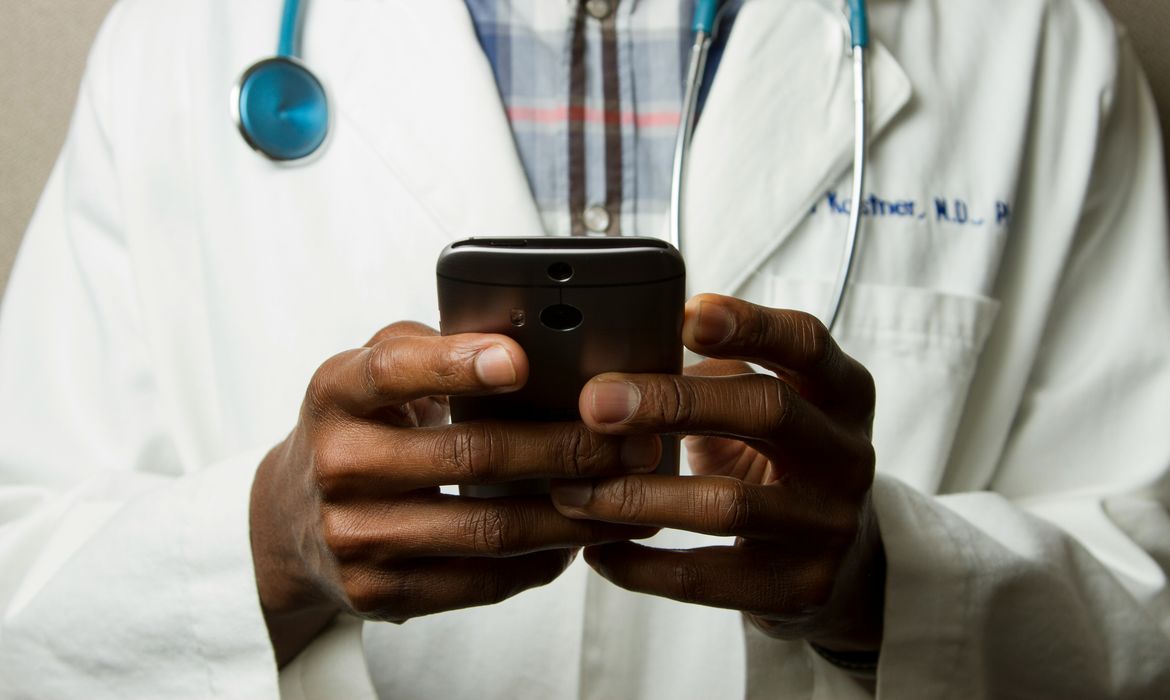 Médico com estetoscópio fala no celular. Foto: National Cancer Institute/Unsplash